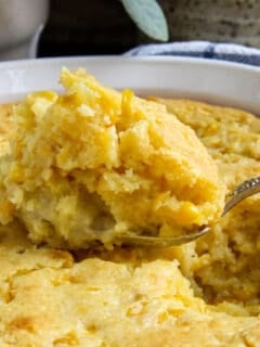 Close up of spoonful of corn soufflé coming out of casserole.