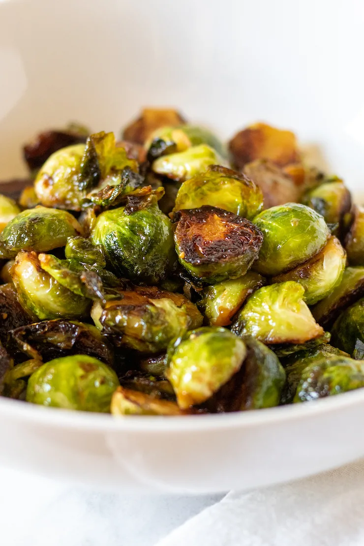 Caramelized stovetop Brussels sprouts in white serving bowl.