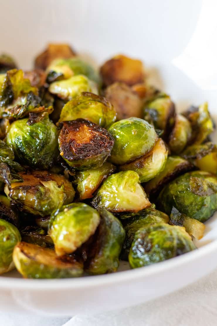 Cooked honey mustard sprouts in white bowl.