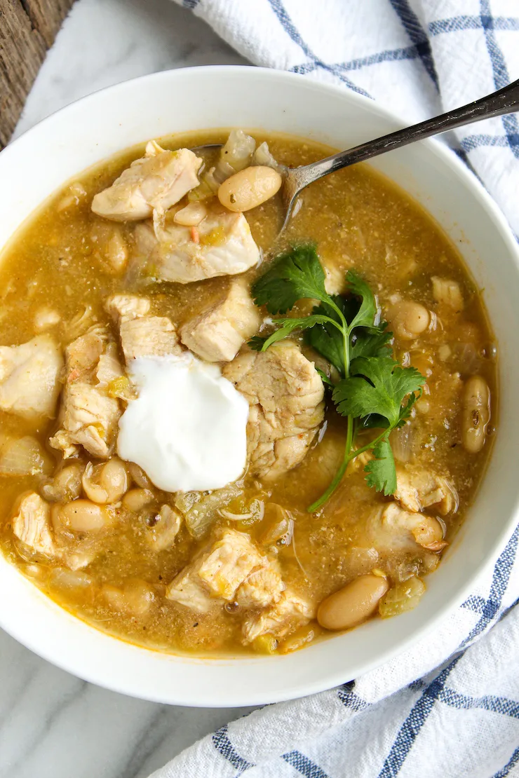 Chili in serving bowl with sour cream and cilantro.