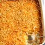 Cheesy potatoes in casserole dish with spoon.