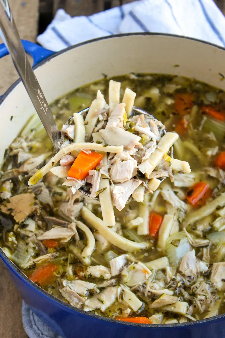 Pot of turkey noodle soup with ladle.