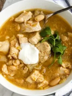 Chicken chili in serving bowl with sour cream.