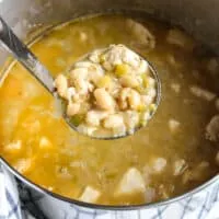 Ladle full of chicken chili held above pot of chili.