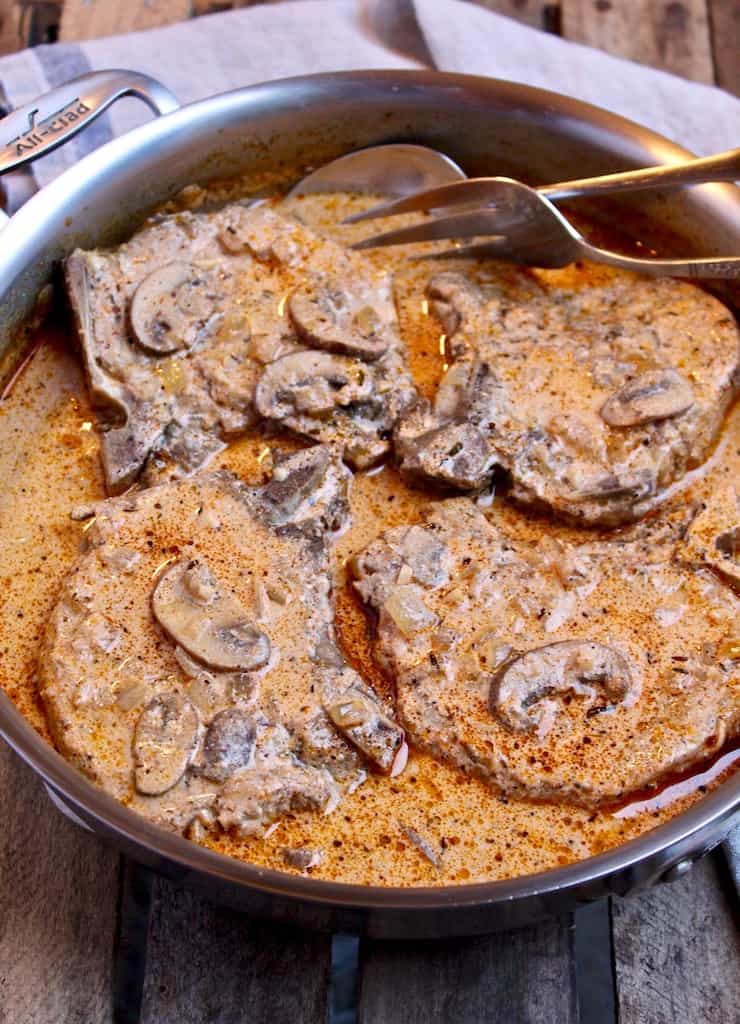 Creamy Cajun Pork Chops, in skillet with serving fork and spoon
