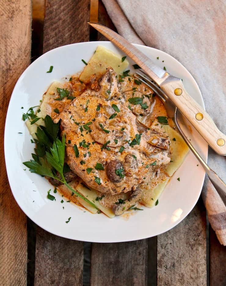 Creamy Cajun Pork Chops, in dish over egg noodles with fork and knife.