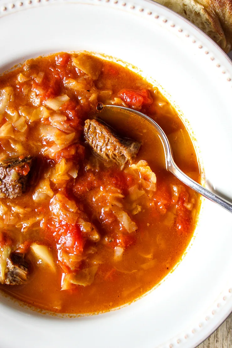 Close up of cabbage soup in servi ng bowl with spoon.