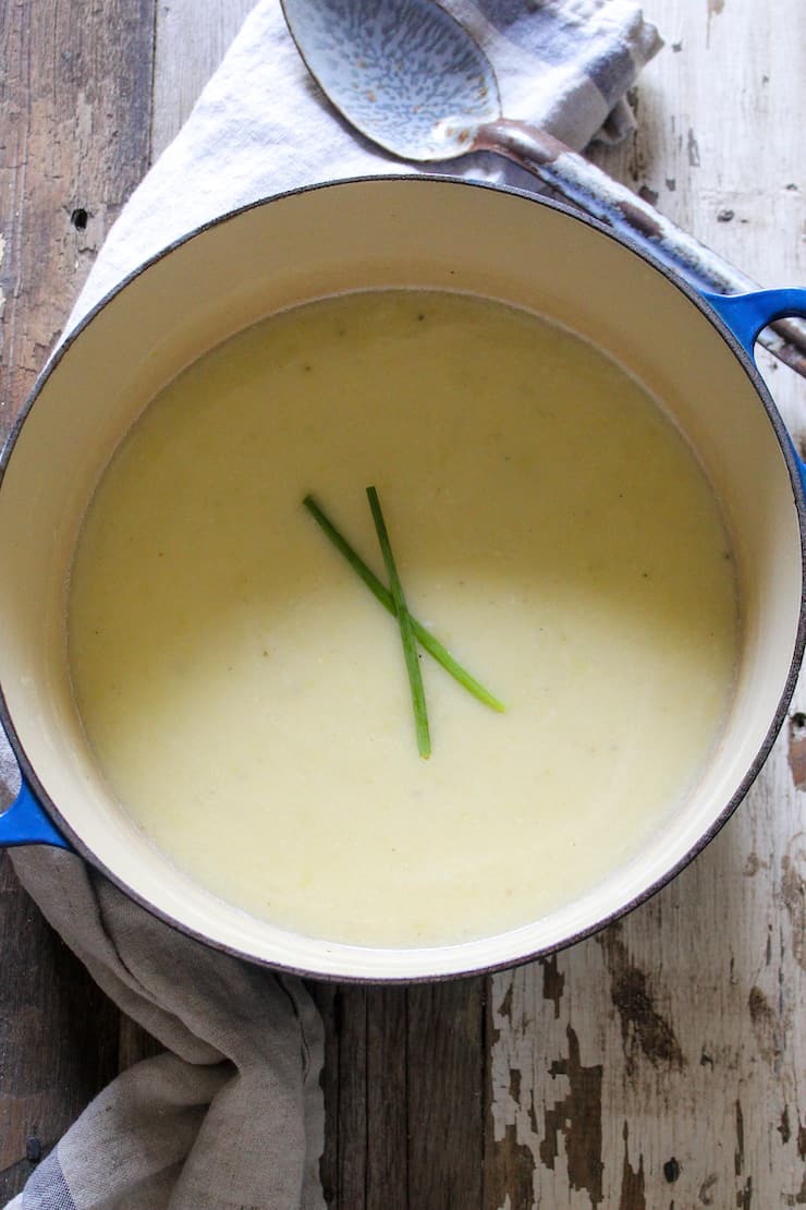 Potato leek soup in pot garnished with chives