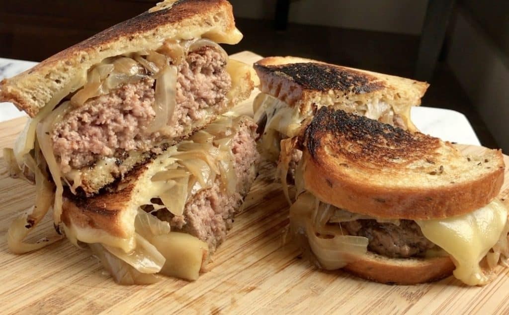 Diner-Style Patty Melts, cut in half and stacked on cutting board.