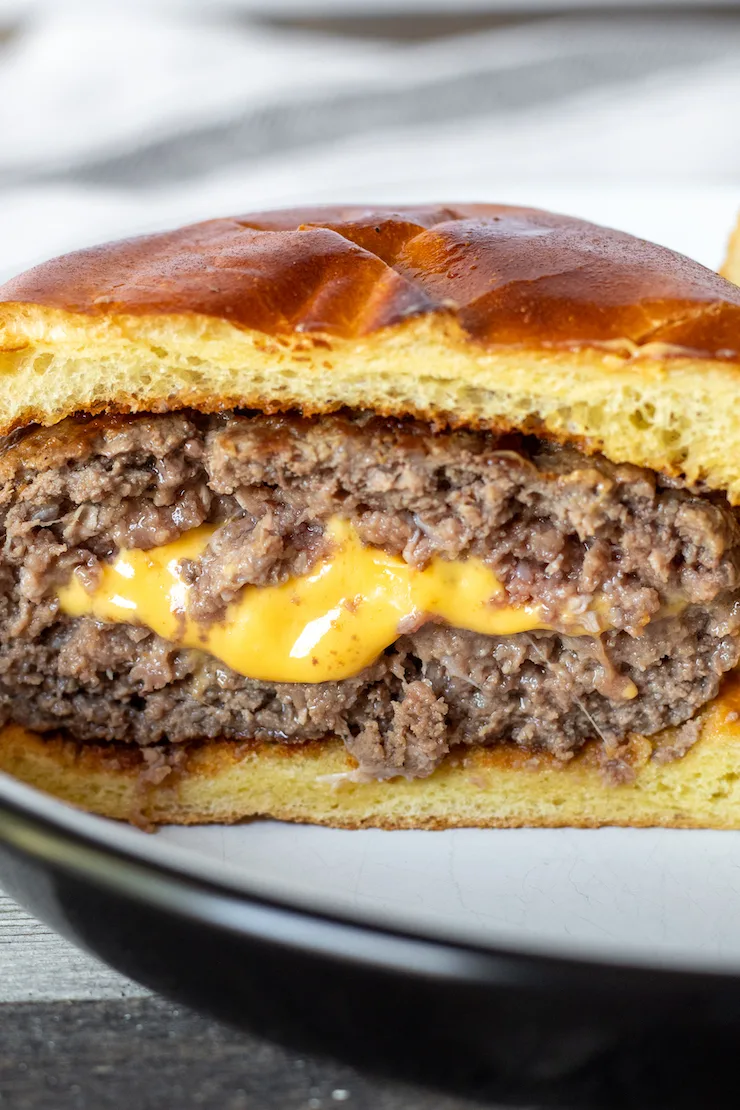 Close up of Juicy Lucy with melted cheese in center of burger.