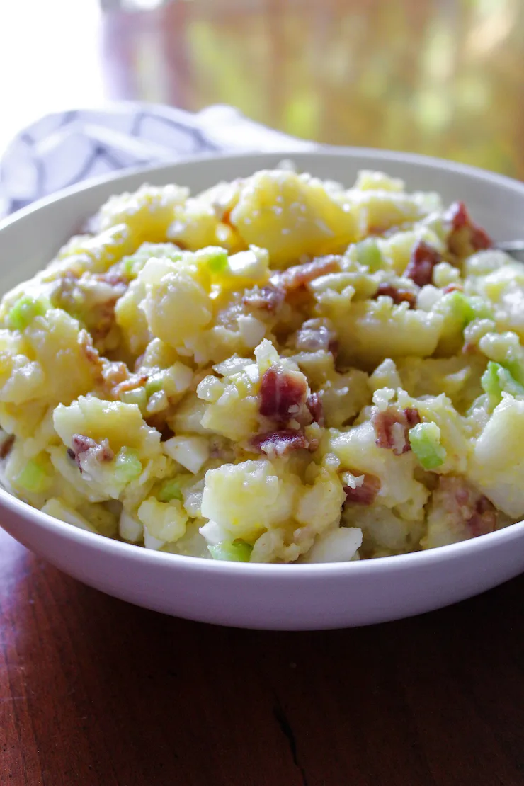 German potato salad in white serving bowl.