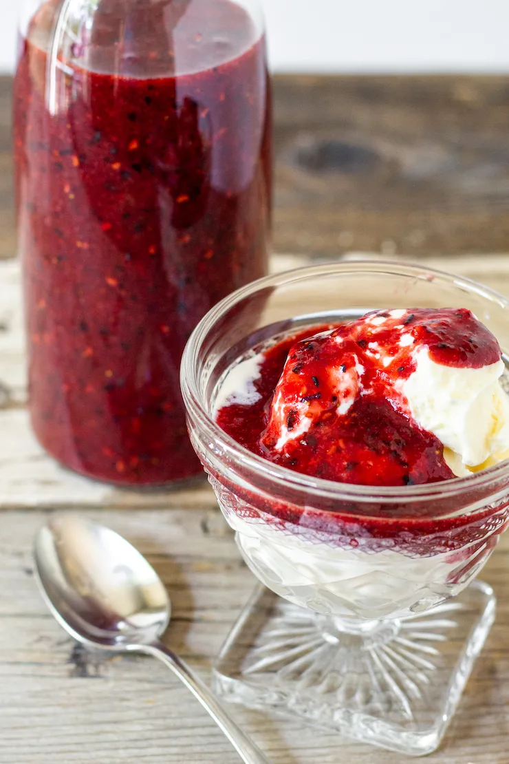 Balsamic berry sauce over ice cream, sauce in bottle in background.