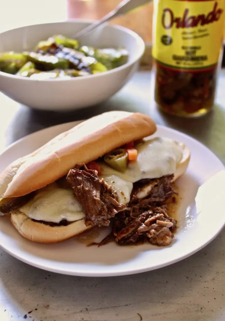 Italian Beef Po' Boys, finished sandwich on plate, with cheese and peppers.