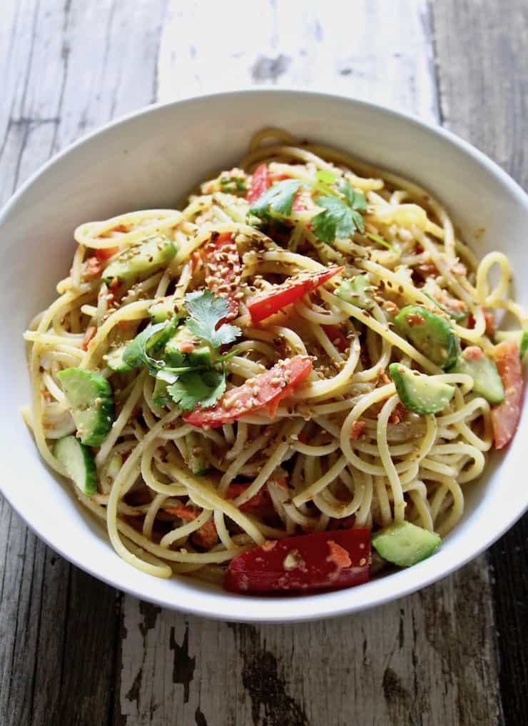 Peanut Sesame Noodles, in serving bowl on board.