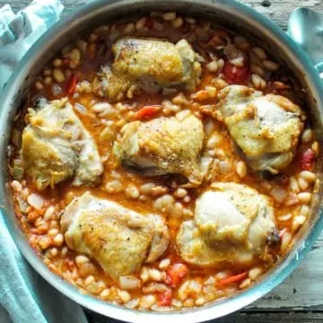 Overhead of chicken and white beans in skillet.