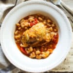 Plated chicken thigh over white beans.