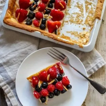 Fruit pizza square on plate with pan in background.