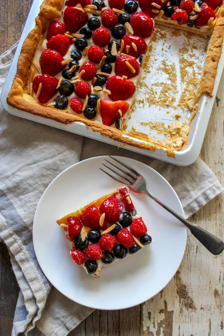 Fruit pizza square on plate with pan in background.