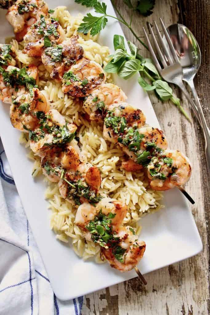 Grilled Shrimp skewers plated with orzo.