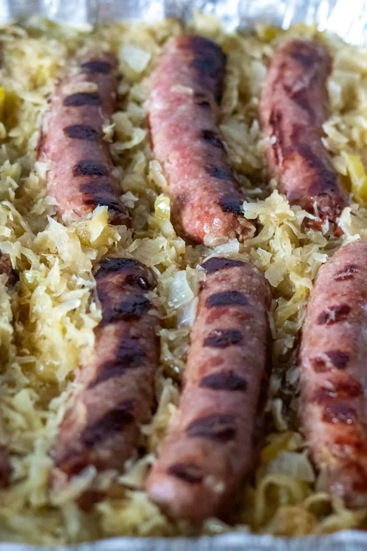 Close up of grilled brats in sauerkraut.