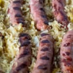 Close up of grilled brats in sauerkraut.