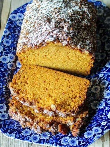 Sliced loaf on blue serving platter with powdered sugar.