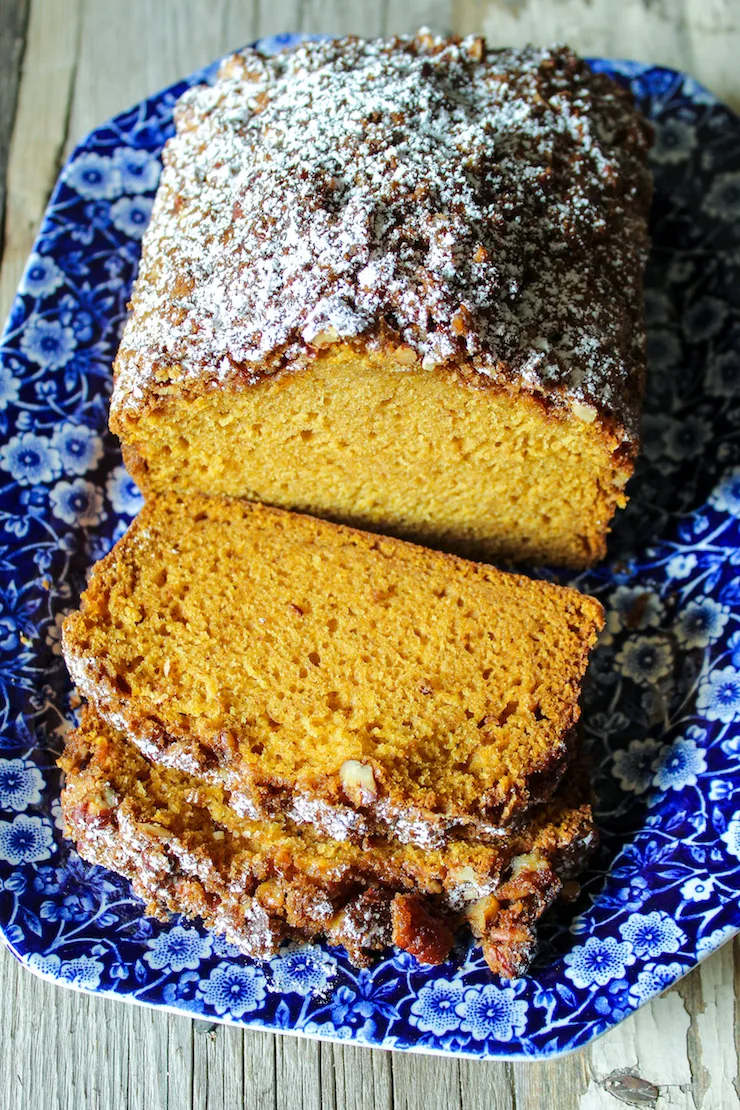 Sliced loaf on blue serving platter with powdered sugar.