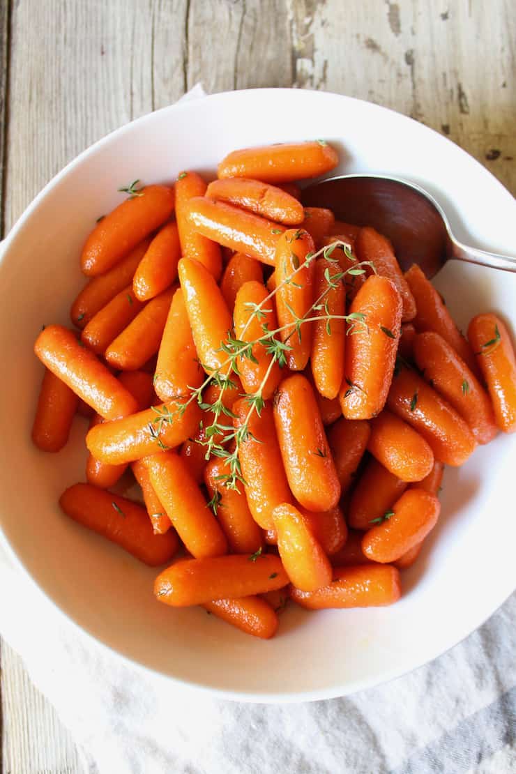 Finished glazed carrots in bowl with spoon.