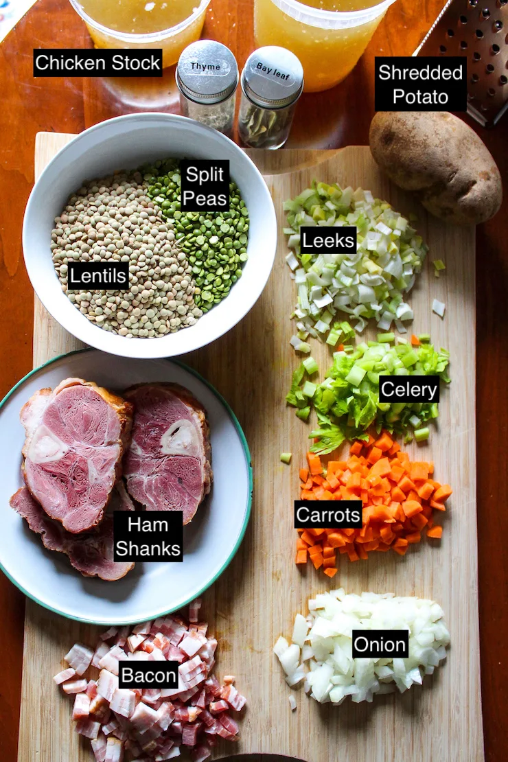 Ingredients for split pea and lentil soup labeled with text on wooden cutting board.