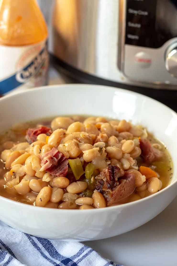 Soup in bowl with Instant Pot and hot sauce in background.