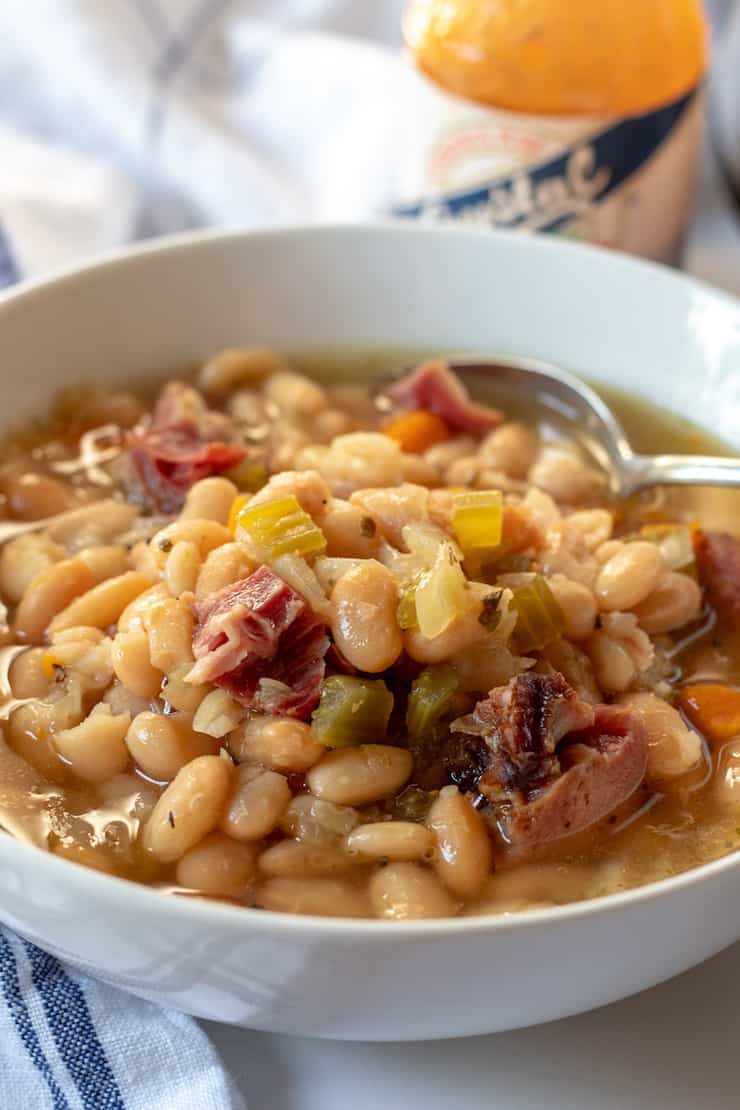 Ham and bean soup in white bowl with spoon.