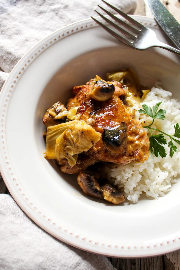 Chicken and artichoke dish in serving bowl with rice.