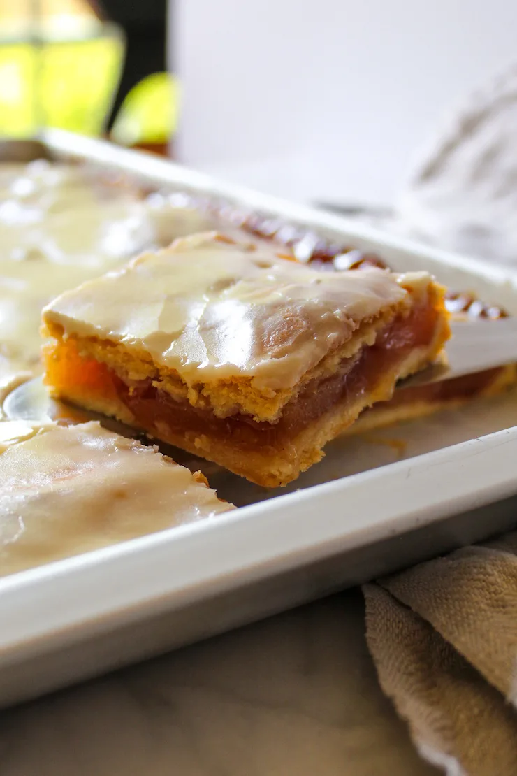 Apple slice on serving knife above pan 