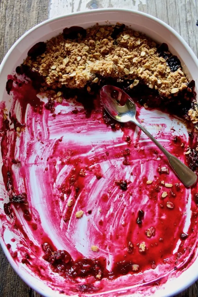 Fresh Blackberry Crisp in baking dish with spoon almost completely eaten.