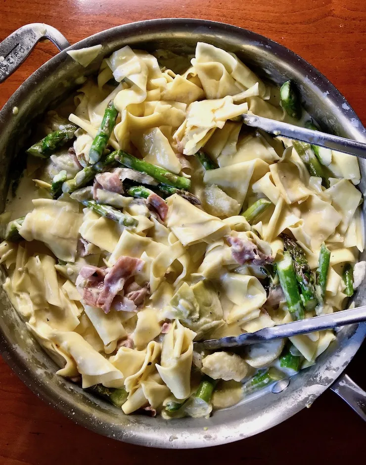 Pasta with Asparagus and Prosciutto overhead photo in skillet with tongs.