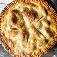 Baked peach pie in pie plate.