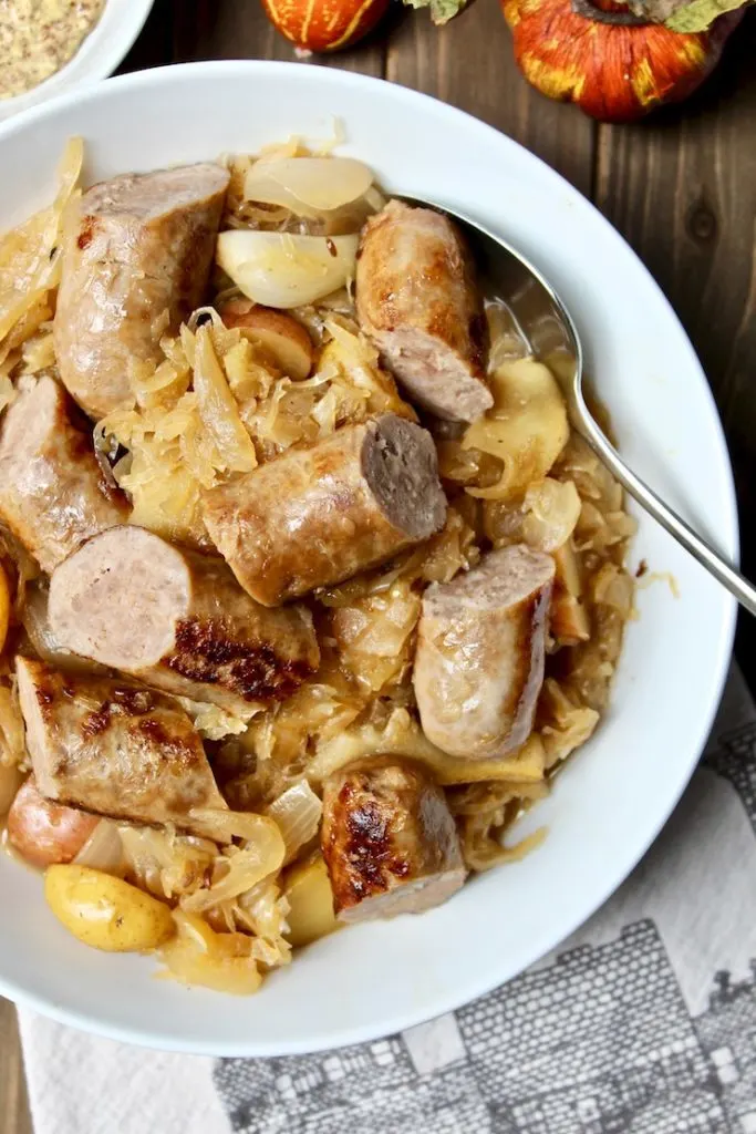 Sausage, Apple, Sauerkraut and Potato Skillet, close up in serving bowl with spoon, sausages cut into pieces