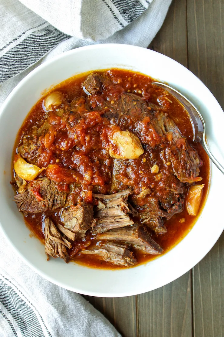 Pot roast and garlic in serving bowl.