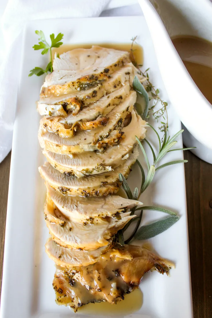 Platter of sliced turkey breast drizzled with gravy.