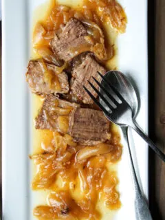 Serving platter of beef with onions spooned over.