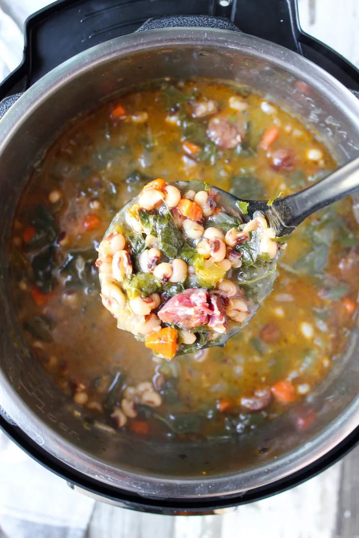 Close up of ladle full of soup over pot.