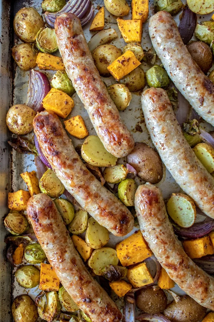 Sausages and caramelized vegetables on sheet pan.