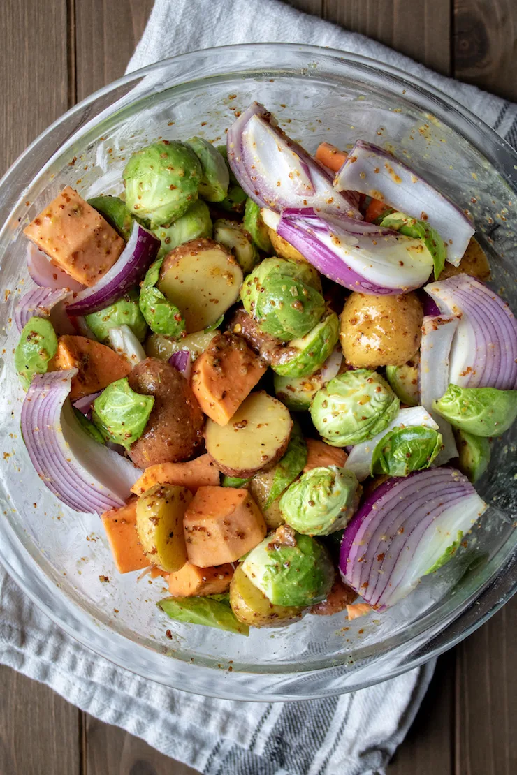 Sausage Sheet Pan Dinner, vegetables in bowl tossed with honey mustard mixture.