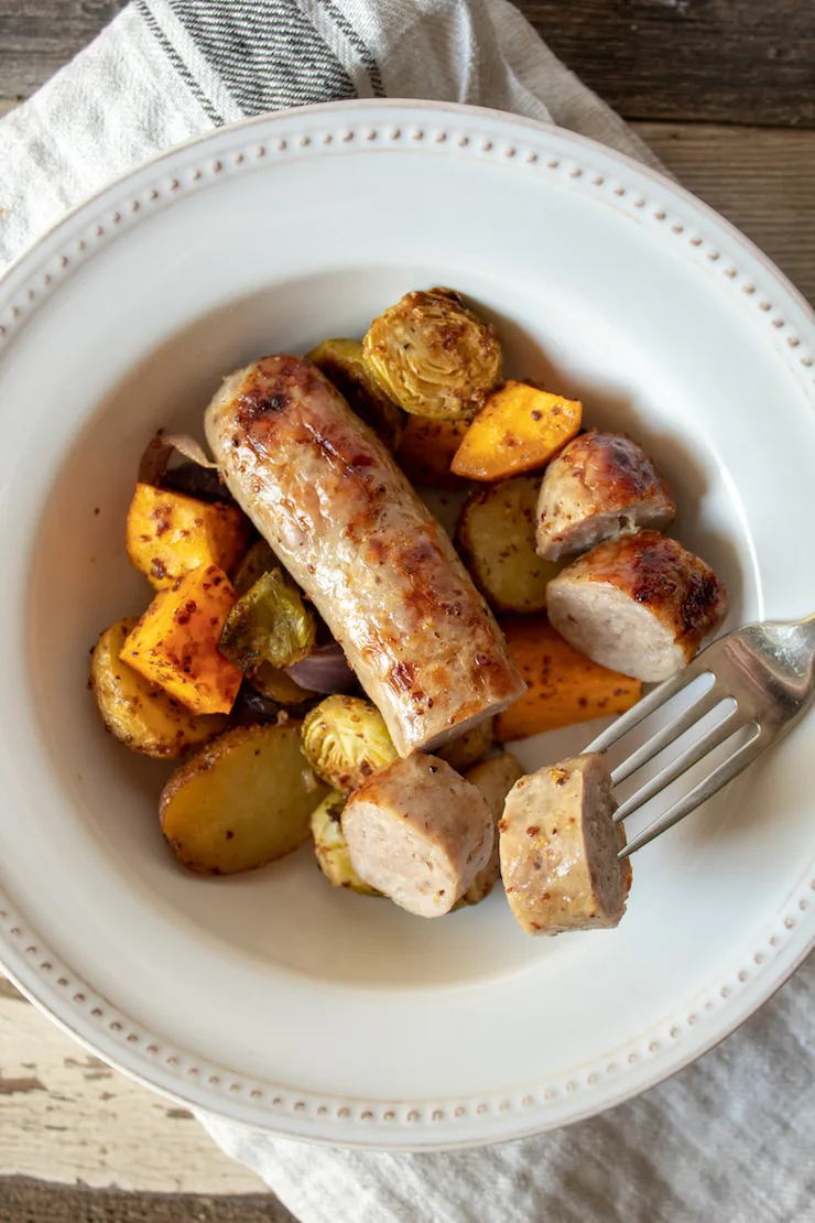 Sausage Sheet Pan Dinner, in serving bowl with sausage slice on fork.