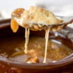 French Onion Soup, close up of onion soup on spoon with melted cheese.