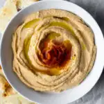 Hummus in serving bowl drizzled with olive oil.