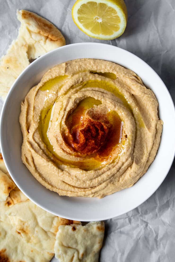 Hummus in serving bowl drizzled with olive oil.