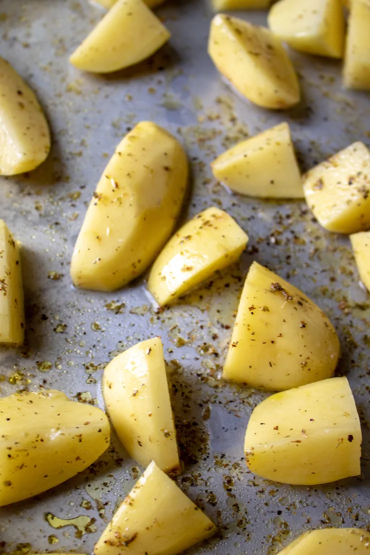 Greek style potatoes on sheet pan ready for oven.