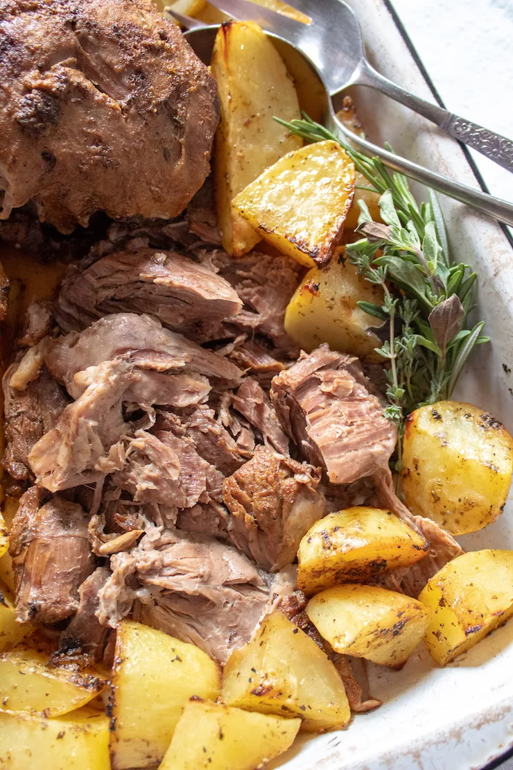 Greek Instant Pot Leg of Lamb, close up in pan with roasted potatoes.