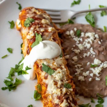 Ground turkey enchilada on plate with refried beans.